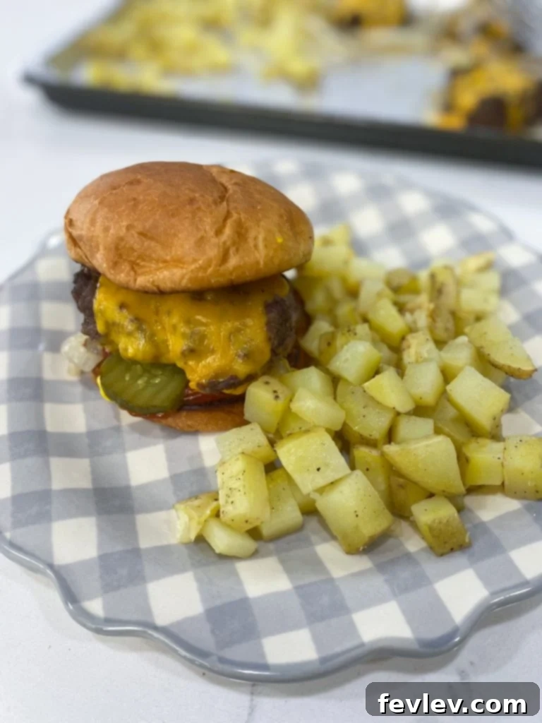 Sheet pan burgers baking in the oven with onions and potatoes