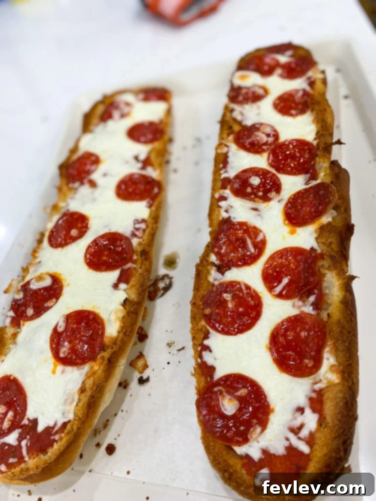Close-up of a partially assembled French Bread Pizza with sauce and cheese, ready for toppings