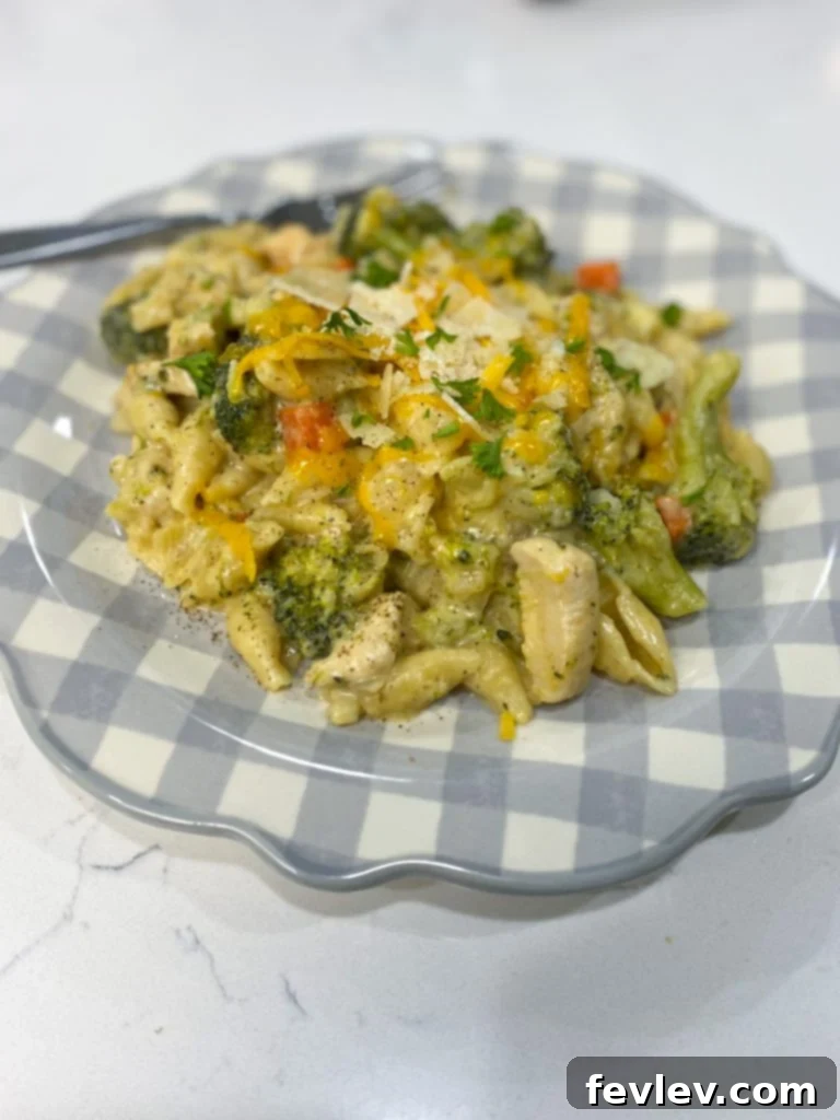 A bowl of freshly made Cheesy Chicken and Broccoli Pasta, garnished with fresh herbs, ready to be served.