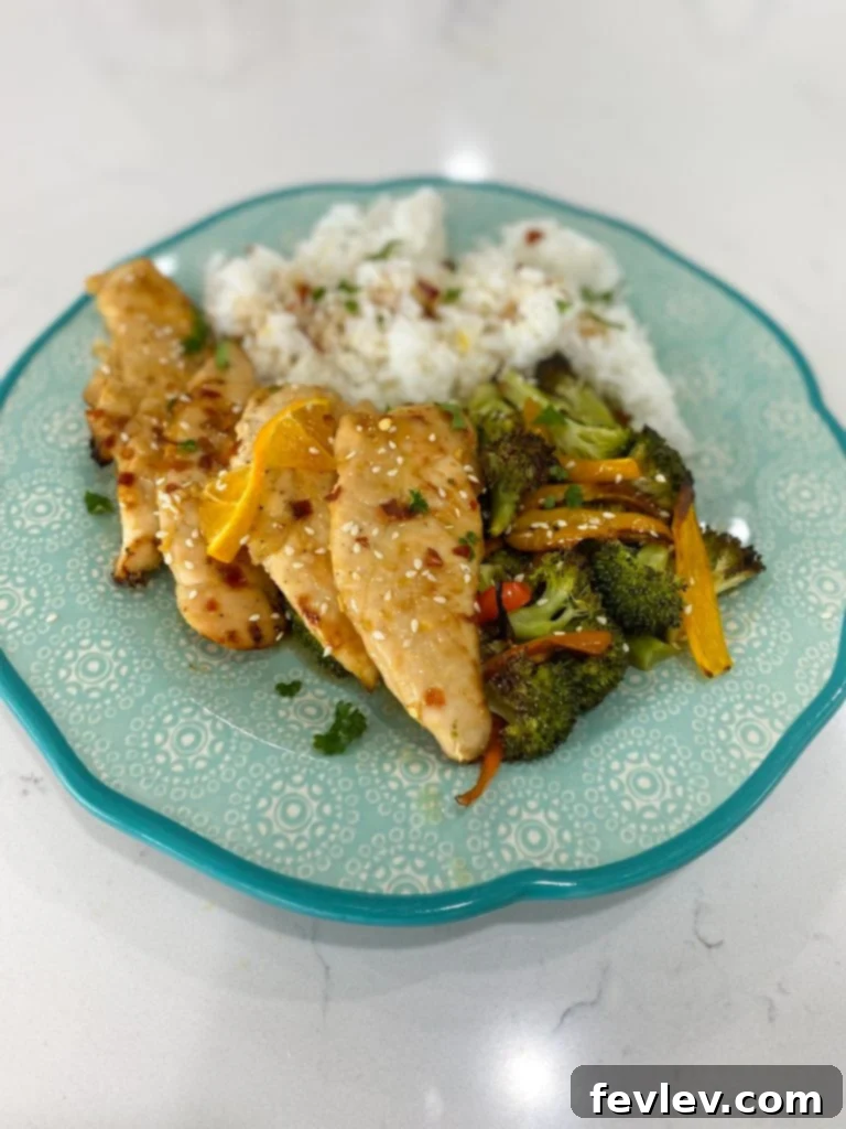 Radiant Orange Chicken 4 Plated healthy orange chicken with white rice, garnished with green onions and sesame seeds, ready to eat.