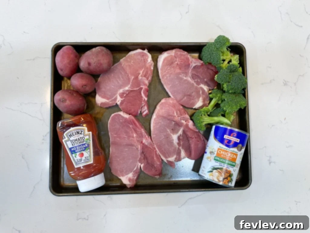 Close-up of a juicy pork chop sheet pan dinner with roasted broccoli and red potatoes, garnished with fresh herbs.