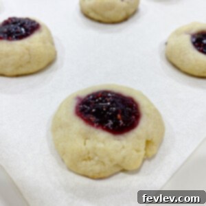 Irresistible Raspberry Thumbprint Cookies with a buttery base and sweet-tart jam filling.