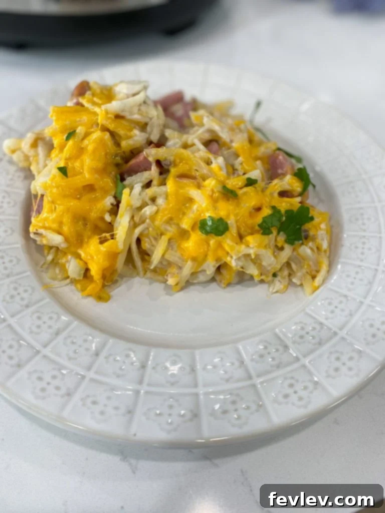 Close-up shot of the uncooked Slow Cooker Hash Brown Casserole ingredients mixed in a slow cooker liner, showing diced sausage, onions, hash browns, and shredded cheese.