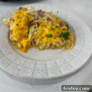 A top-down view of a delicious Slow Cooker Hash Brown Casserole with ham and biscuits, garnished with fresh herbs.