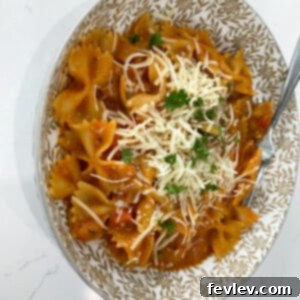 Close-up of freshly cooked One-Pot Italian Vegetable Pasta in a bowl, garnished with fresh parsley and shredded mozzarella.