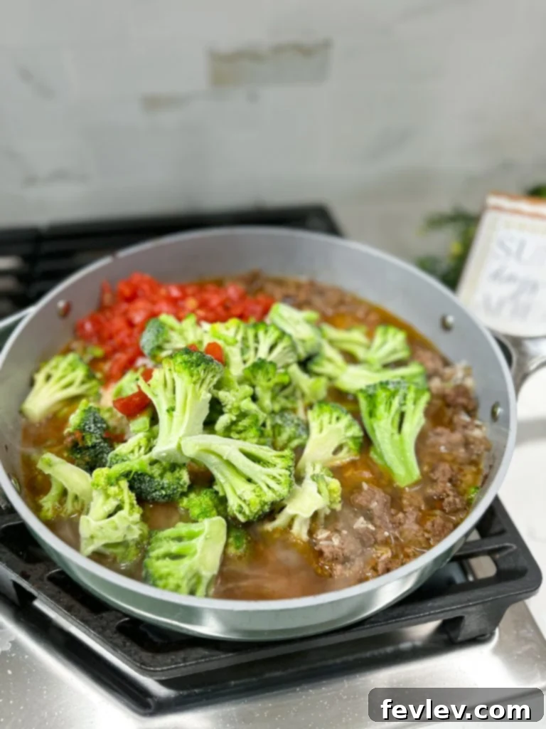 A top-down view of a vibrant Mexican Beef and Rice Skillet, garnished with fresh cilantro and shredded cheese, ready to be served in a rustic cast iron pan.