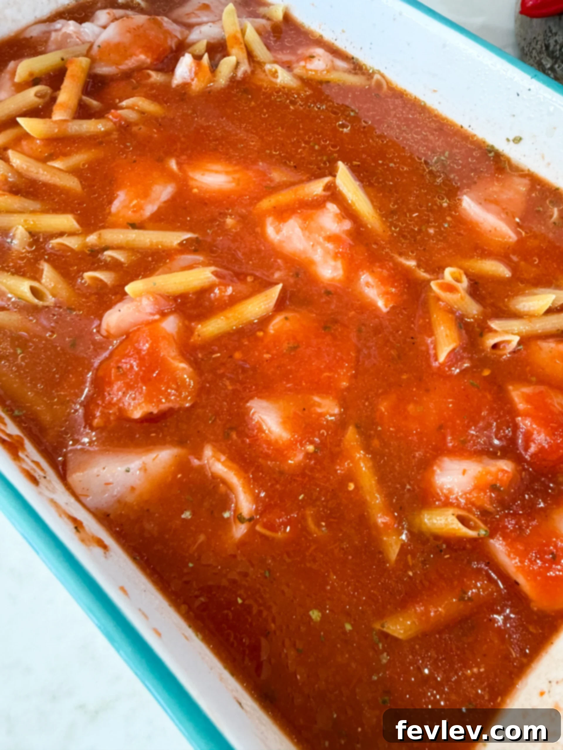 Mixing pasta, sauce, and chicken in a 9x13 baking dish before baking