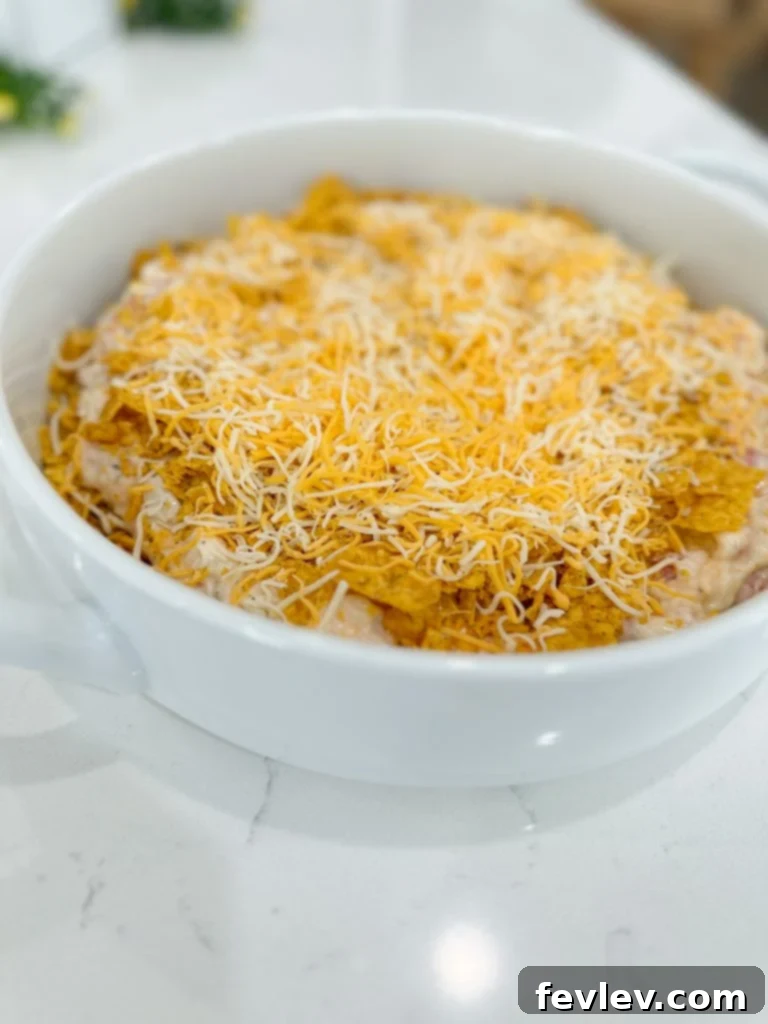 Crushed Cool Ranch Doritos forming the base layer of the chicken casserole in a baking dish.