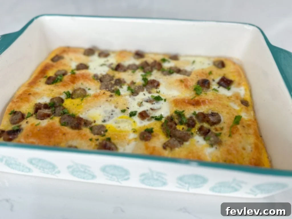 Freshly baked Crescent Roll Sausage Egg Casserole, golden and bubbly, with a sprig of fresh herbs