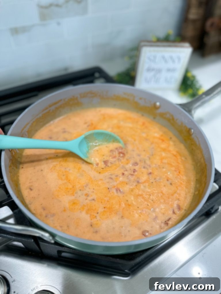 Close-up of the creamy tomato bacon sauce simmering in a pan, showcasing its rich texture