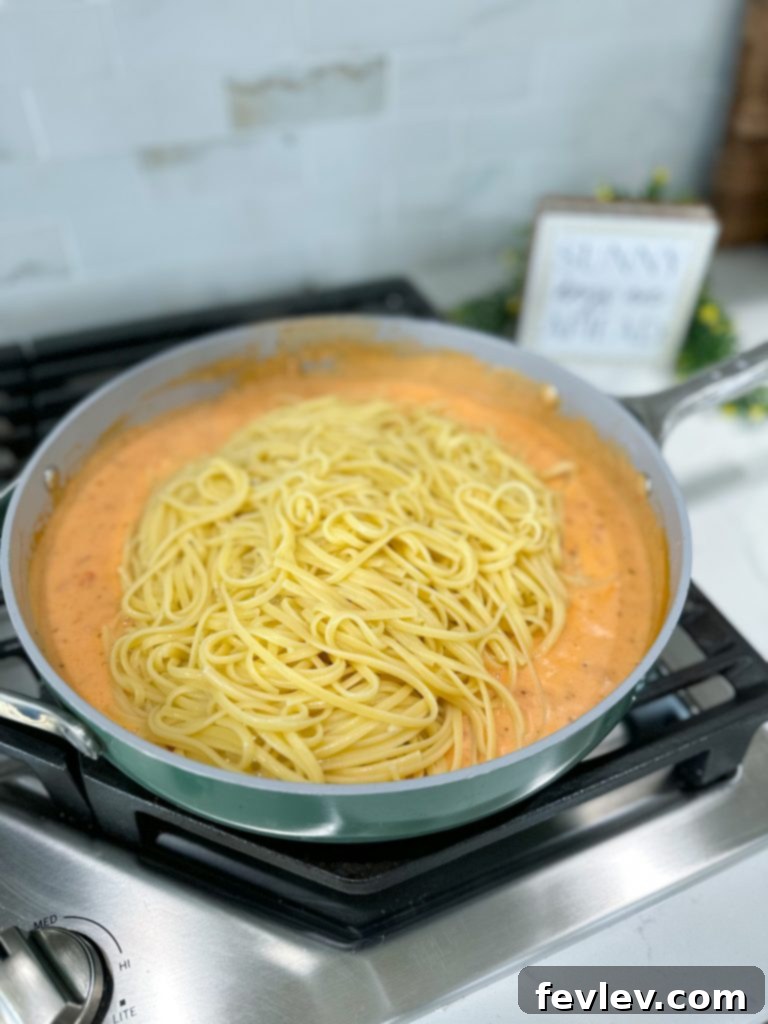 Serving of Creamy Tomato Bacon Pasta in a bowl, garnished with parsley and Parmesan cheese
