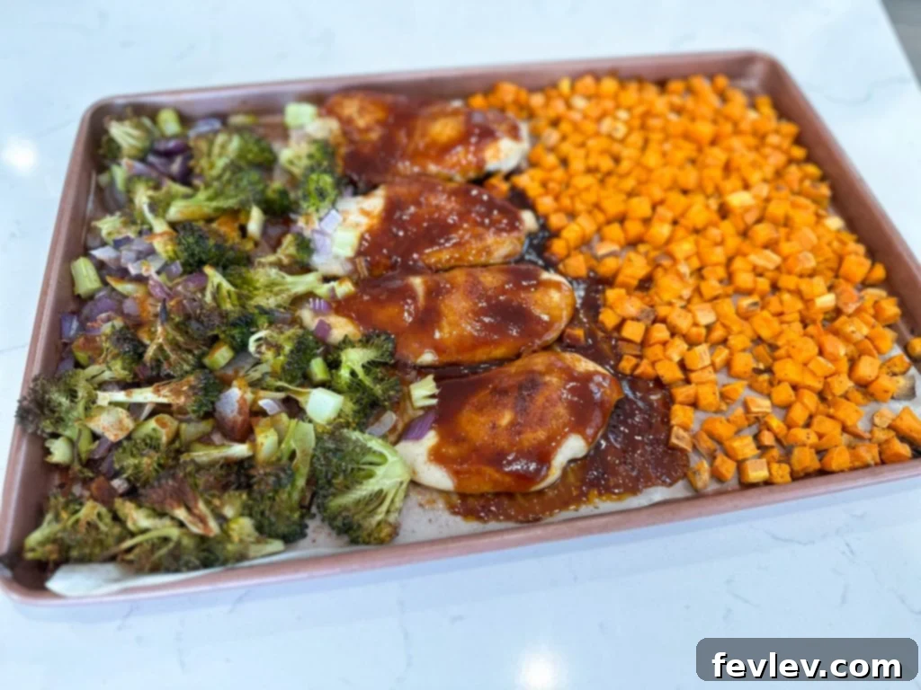 Close-up of perfectly seasoned chicken and diced sweet potatoes on a sheet pan, ready for baking.