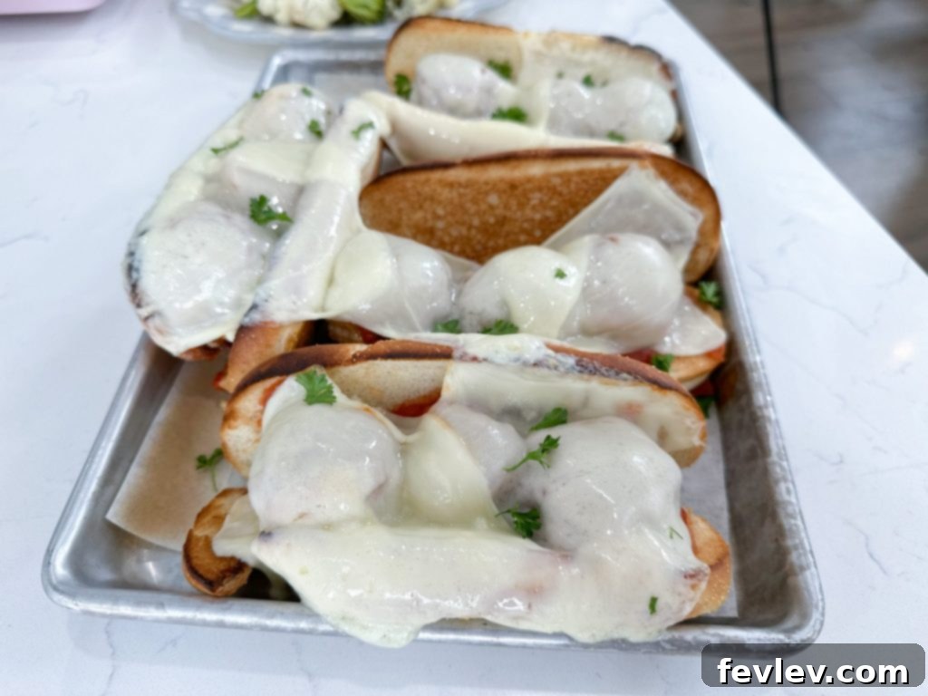 Finished Sheet Pan Turkey Meatball Subs with melted mozzarella and roasted vegetables, ready to serve.