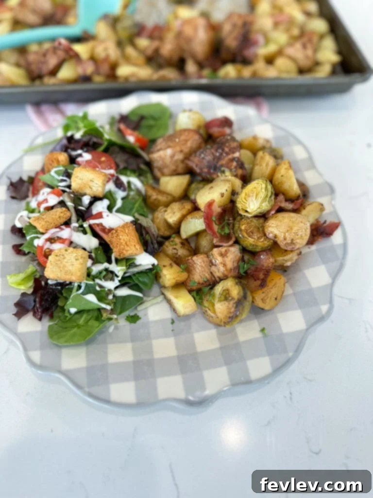 Serving of Sheet Pan Balsamic Chicken with crispy bacon, potatoes, and Brussels sprouts on a plate, garnished