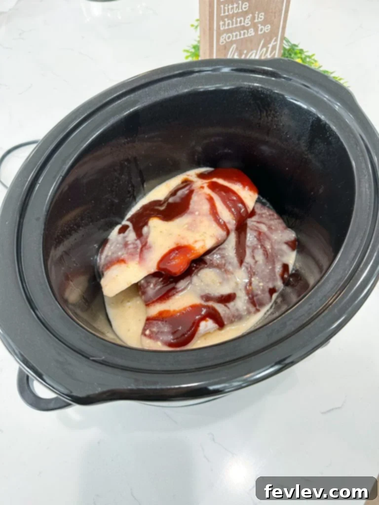 Tender Slow Cooker BBQ Chicken Perfection 2 Slow Cooker BBQ Chicken served on a bun with coleslaw