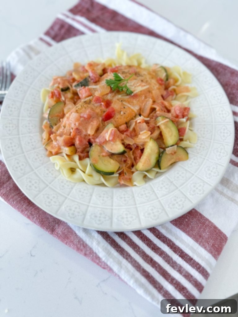 One-Pan Creamy Chicken with Zucchini and Tomatoes 4 A finished plate of Creamy Chicken Skillet with Tomatoes and Zucchini, served alongside egg noodles.