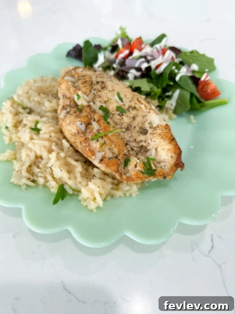 A serving of One Pot Lemon Chicken and Rice with a side of fresh lemon wedges and herbs, ready to eat.