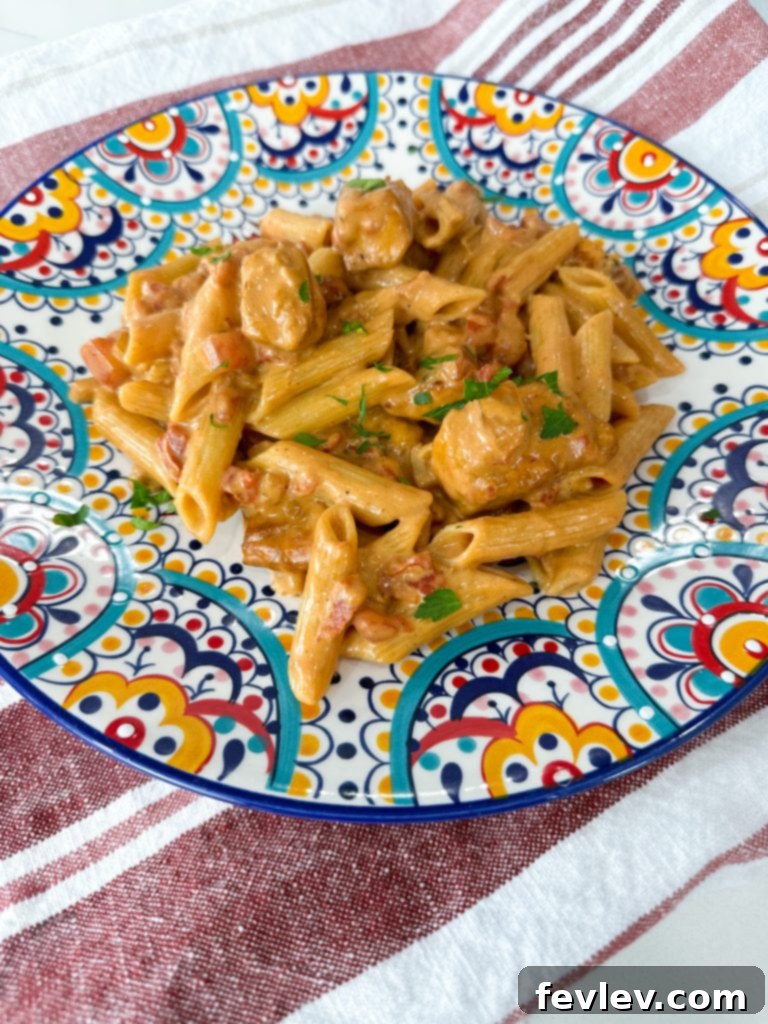 A serving of Tomato Honey Pasta with Chicken in a white bowl, ready to be eaten.