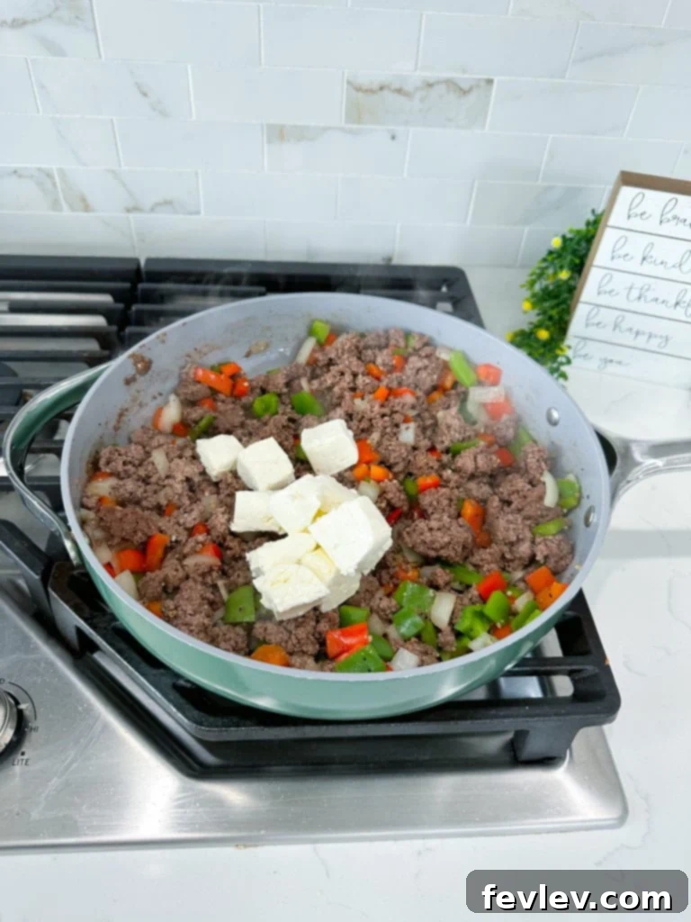 Cheesy Philly Cheesesteak Bake 4 cooked ground beef with bell peppers, onions, and melted cream cheese in a skillet