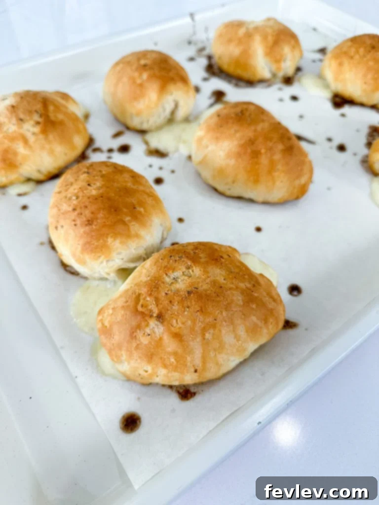 Stuffed Ham and Cheese Biscuits brushed with a savory seasoning mixture, ready for baking.