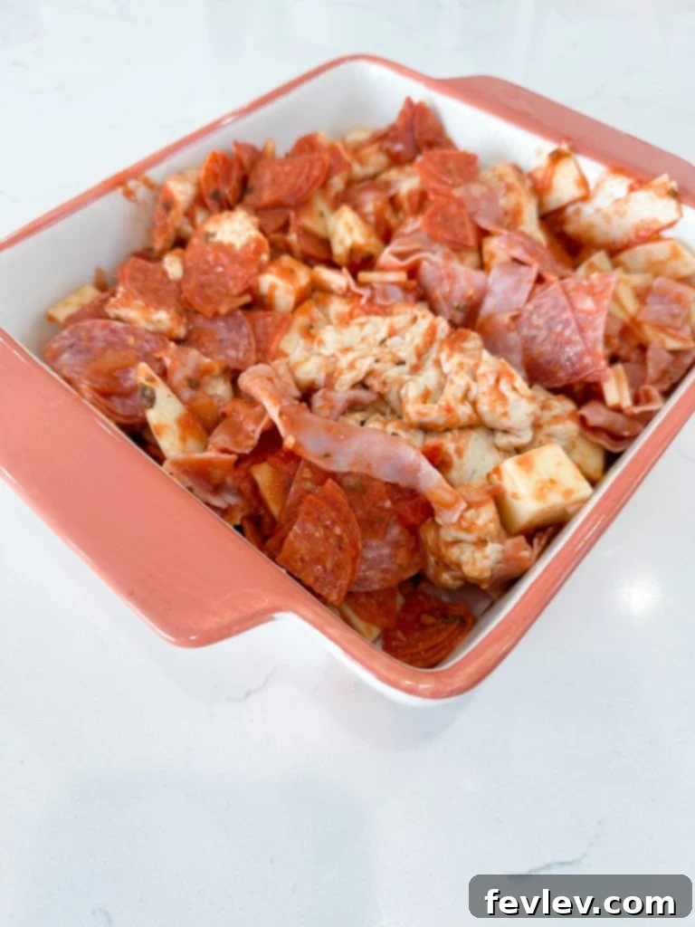 Ultimate Italian Sub Bake 4 A large mixing bowl filled with the Italian Sub Casserole ingredients – cut biscuits, meats, cheeses, and marinara – perfectly combined before transferring to a baking dish.