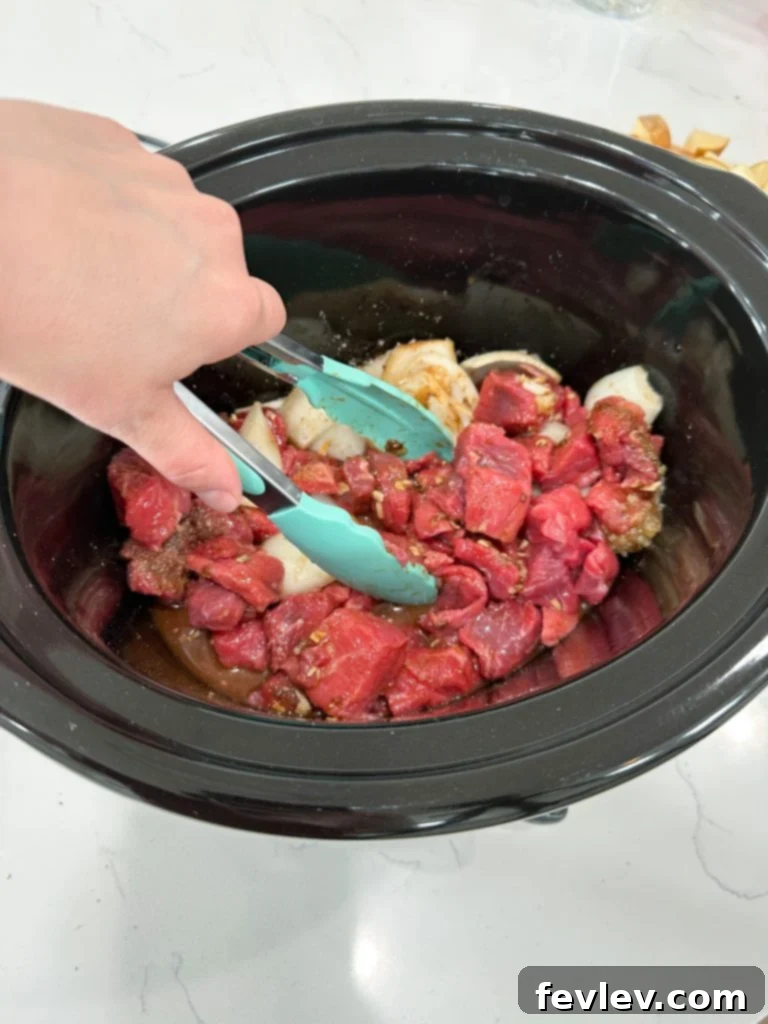 Adding beef and seasonings to the slow cooker