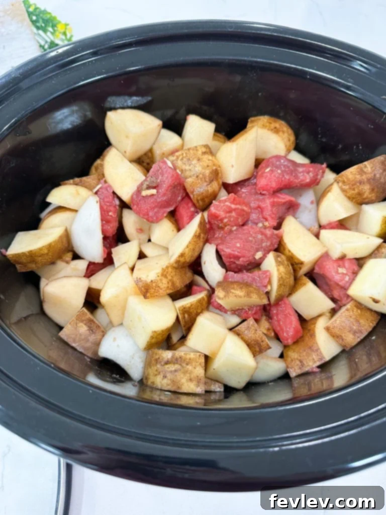 Adding cubed potatoes to the slow cooker with beef