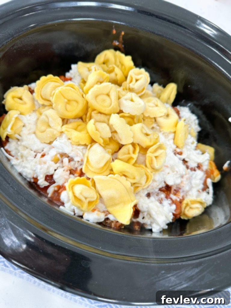 The Ultimate Slow Cooker Sausage Tortellini Bake 5 Preparing the slow cooker with non-stick spray for lasagna layers