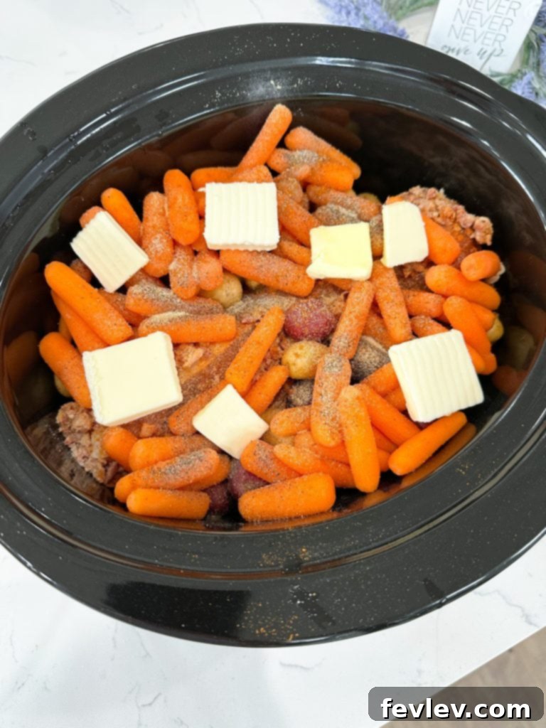 Melt-in-Your-Mouth Slow Cooker Pork Tenderloin 4 Seasoned baby potatoes and carrots generously topped with thin slices of butter in a slow cooker.