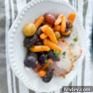 Close-up of Slow Cooker Pork Tenderloin with Vegetables, garnished and ready to eat.