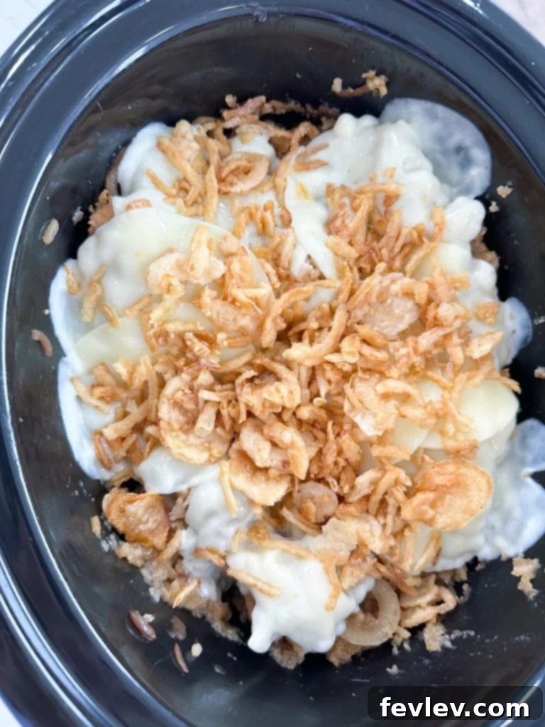 The Slow Cooker French Onion Chicken and rice mixture after the main cooking phase, showing tender chicken and fluffy rice soaking in the rich sauce, ready for the final toppings.