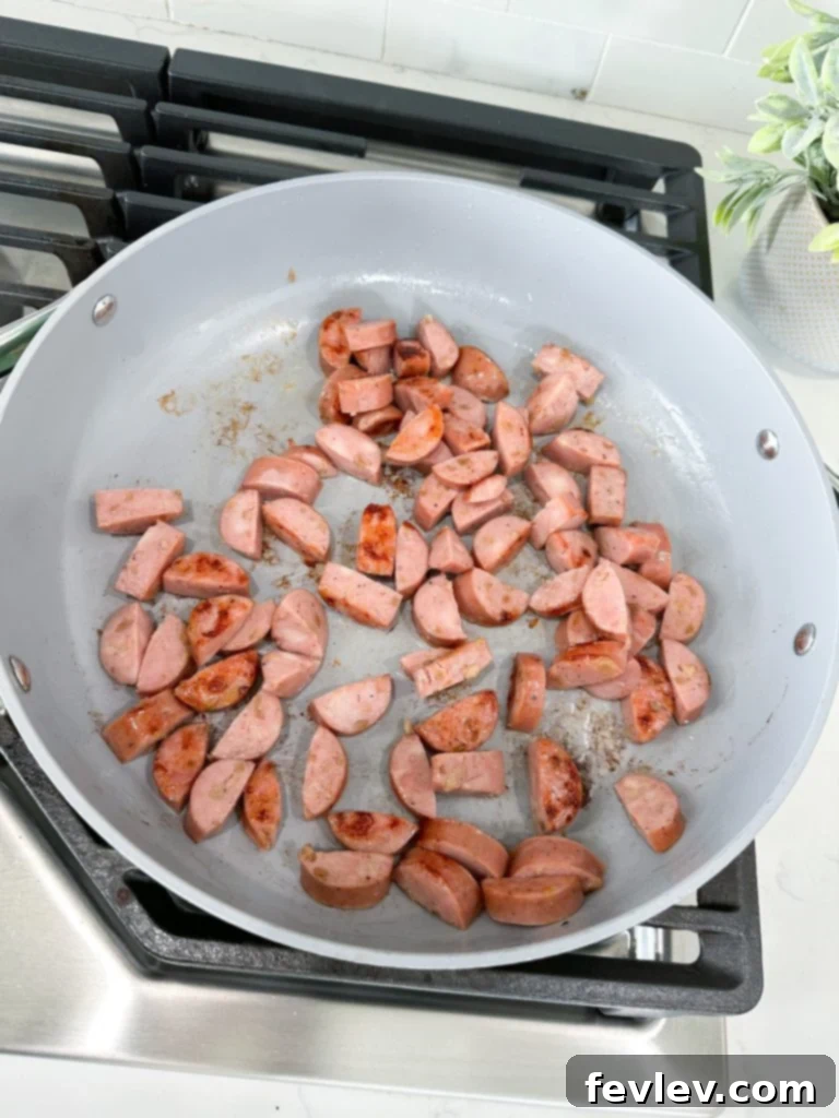 Slicing pre-cooked chicken sausage into half-moon shapes for the skillet meal.