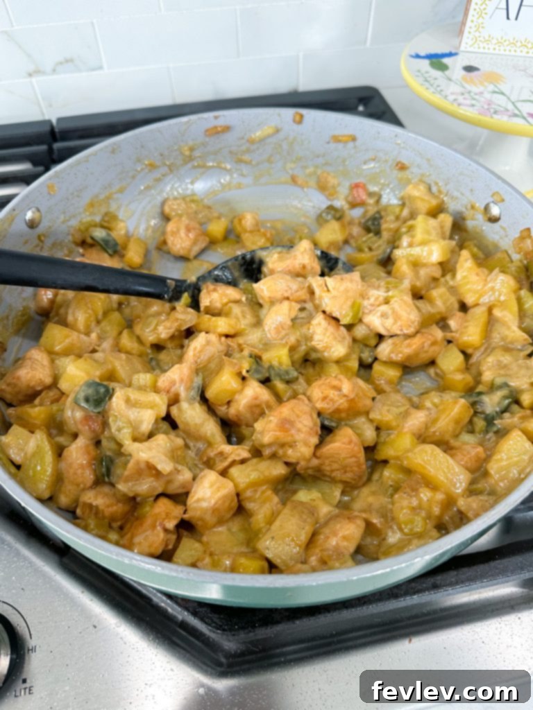 finished green chile chicken with potatoes in a skillet, topped with cheese