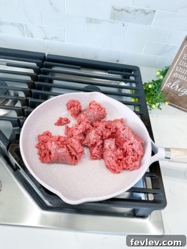 Preparing ingredients for Dorito Taco Pie: cooked ground beef, crushed Doritos, crescent dough