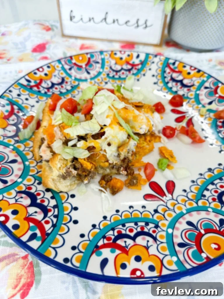 A slice of golden-brown Dorito Taco Pie garnished with fresh toppings