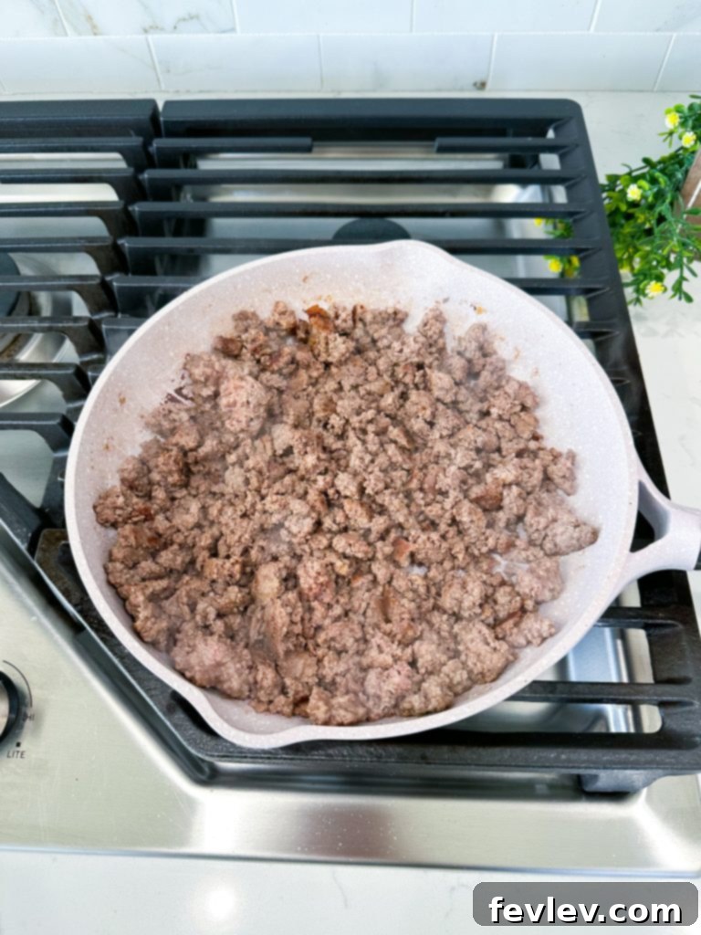 Ground beef cooking in a skillet, seasoned with taco seasoning
