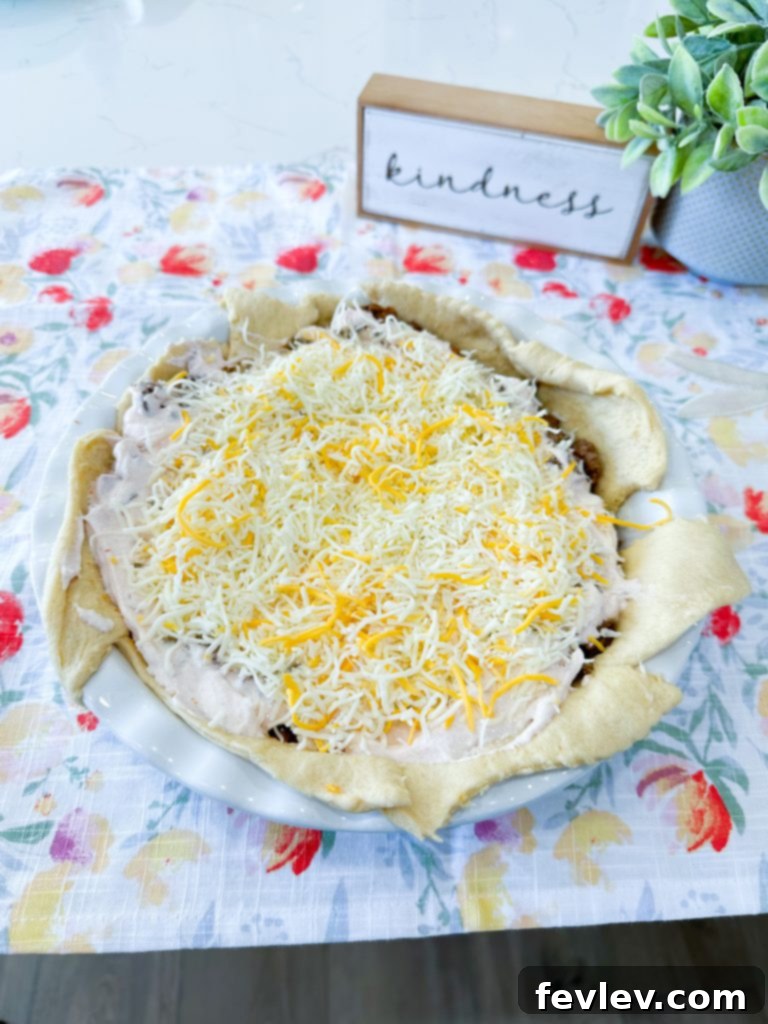 Sour cream and salsa mixture being spread over the ground beef layer