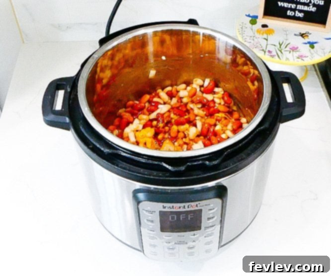 Instant Pot filled with mixed beans and sauce, ready for pressure cooking.