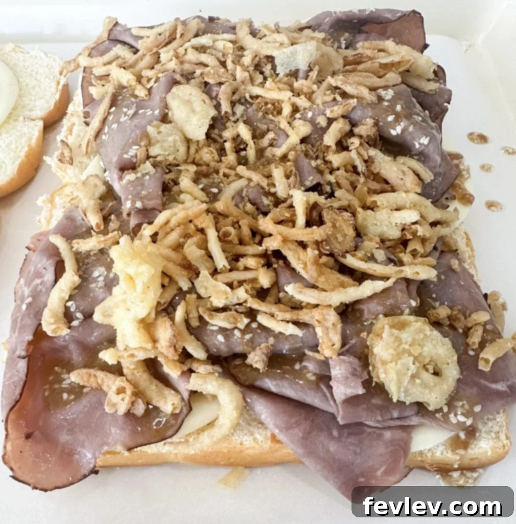 Assembling French Dip Sliders on Hawaiian rolls with roast beef and provolone cheese