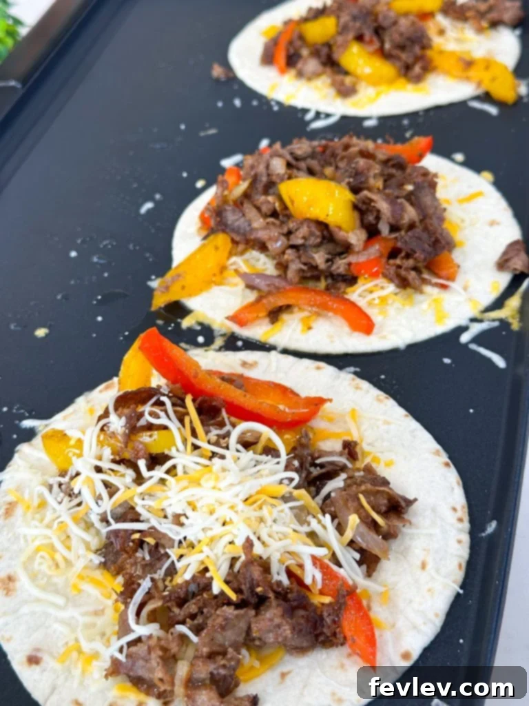 Assembling a steak fajita quesadilla on a griddle