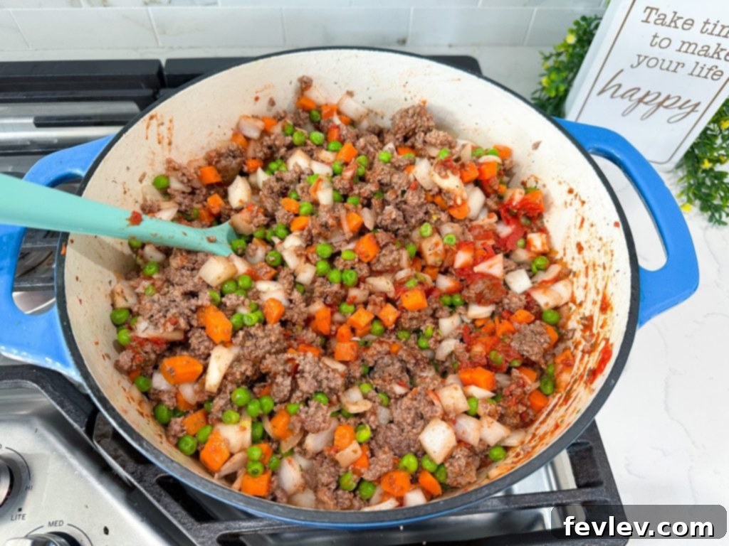 Ground beef and diced onion browning in a skillet for Shepherd's Pie.