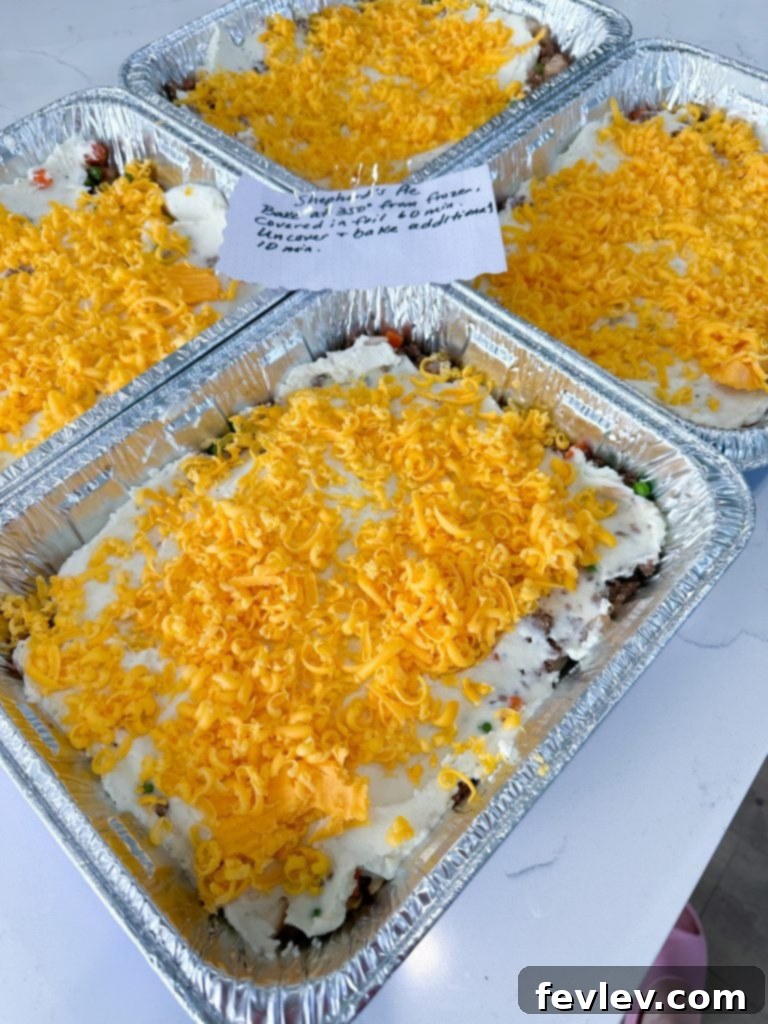Assembling Shepherd's Pie with ground beef mixture at the bottom of a disposable pan.