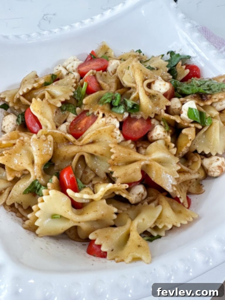 Fresh Caprese Pasta Salad with Zesty Balsamic 2 Vibrant Caprese Pasta Salad with Balsamic Vinaigrette, showcasing fresh cherry tomatoes, mozzarella pearls, and basil.