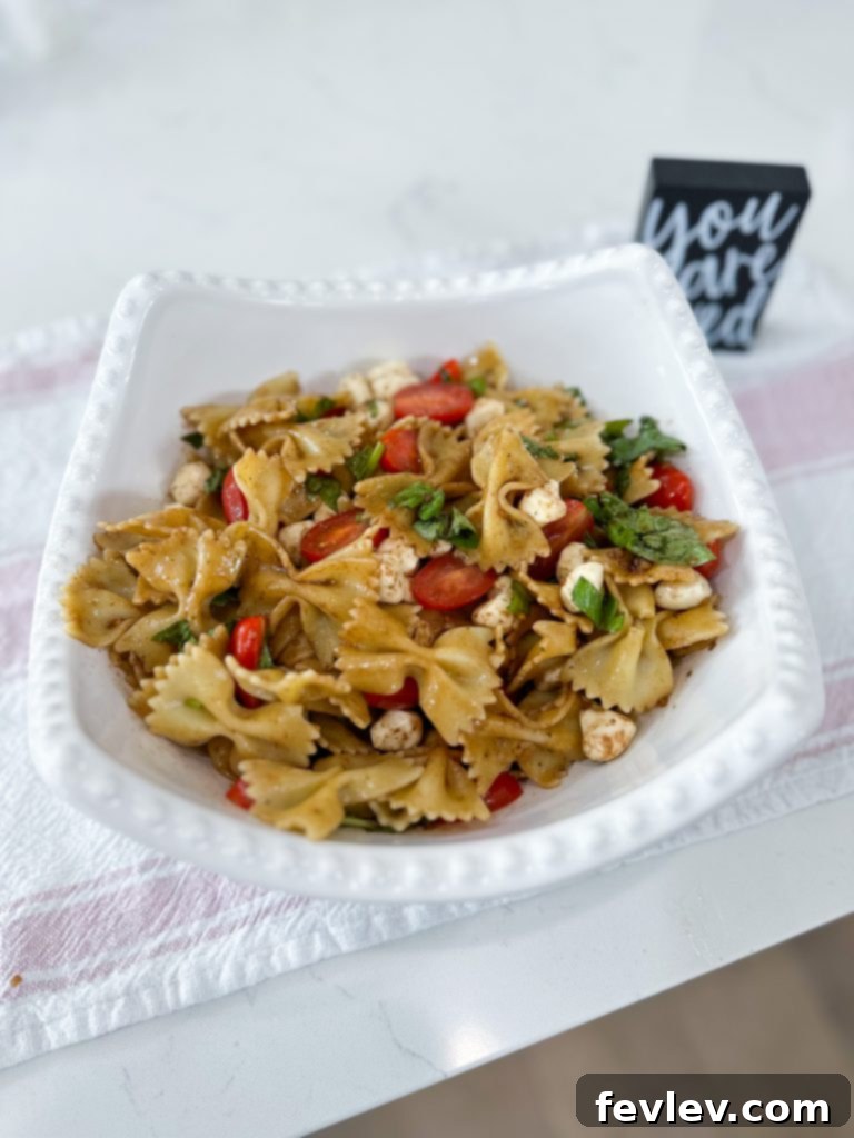 Fresh Caprese Pasta Salad with Zesty Balsamic 8 Mixing fresh basil into the Caprese pasta salad ingredients.
