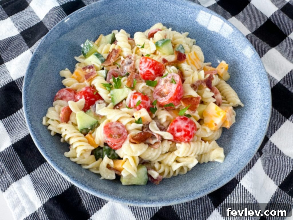 Ranch Kissed Italian Pasta Salad 2 A vibrant bowl of Italian Ranch Pasta Salad, featuring rotini pasta, crisp bacon, mini pepperoni, fresh cucumber, and cherry tomatoes, all coated in a creamy, zesty dressing.