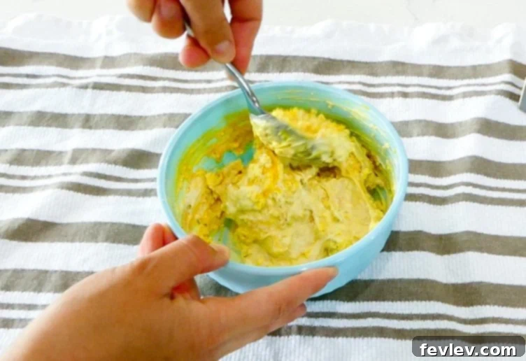 Deviled egg dressing ingredients being mixed with mashed yolks.