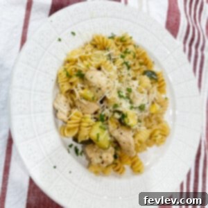 Delicious Lemon Butter Chicken with Pasta, garnished with fresh parsley and lemon slices, served in a wide bowl.