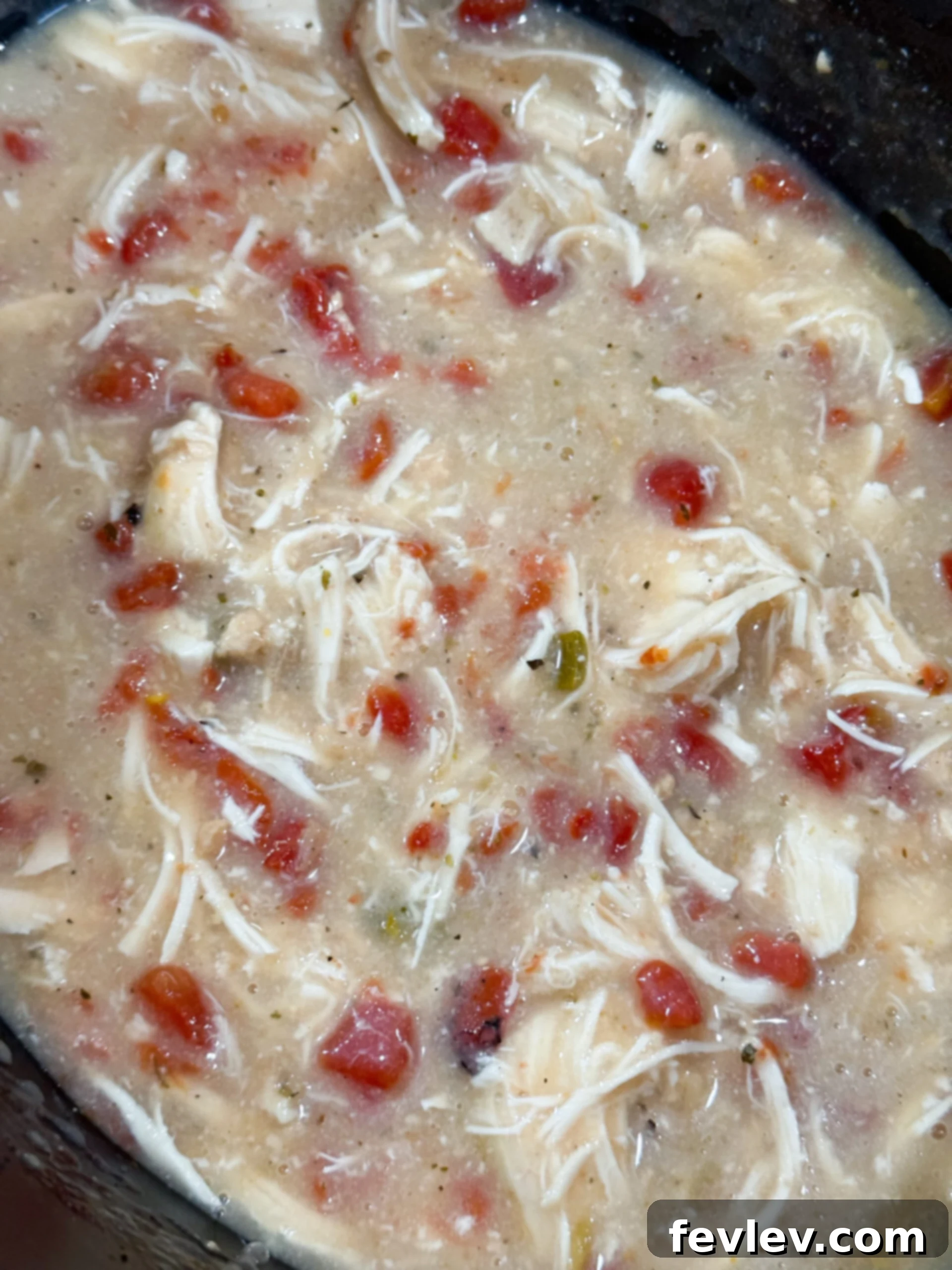 Velvety Slow Cooker Rotel Chicken Pasta 6 Cooked chicken being shredded directly in the creamy Rotel sauce within the slow cooker.