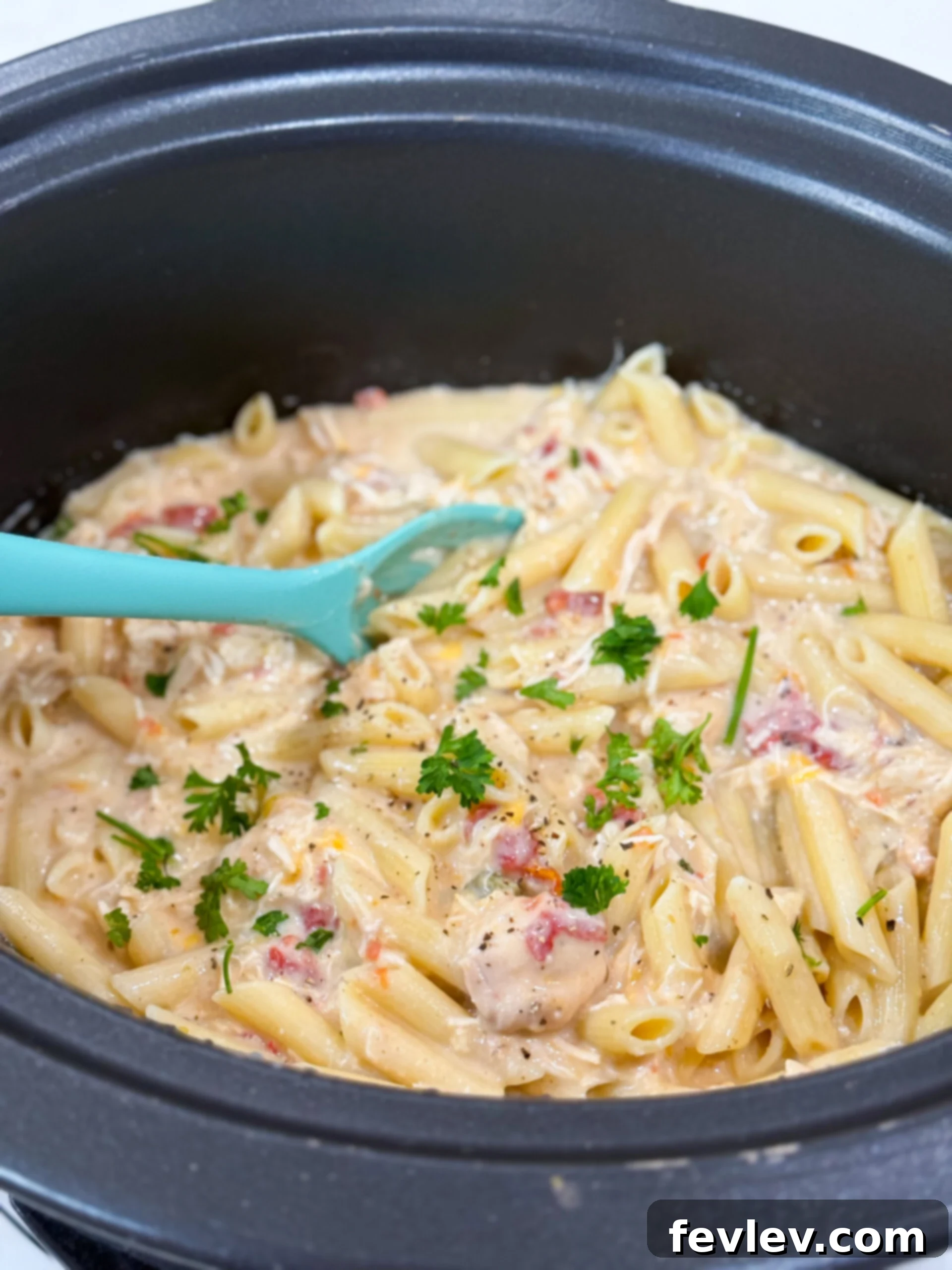 Velvety Slow Cooker Rotel Chicken Pasta 8 Slow cooker filled with creamy chicken pasta, topped with a sprinkle of extra cheese and herbs.