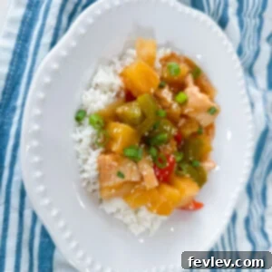 Delicious Slow Cooker Sweet and Sour Chicken served over rice with bell peppers and pineapple